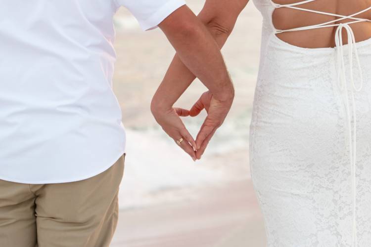 couple making a heart with their hands on a beach